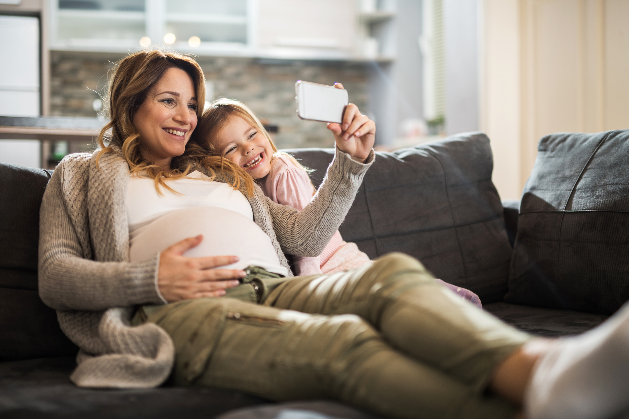 Mom and Daughter sitting on the couch preparing to take a selfie photo